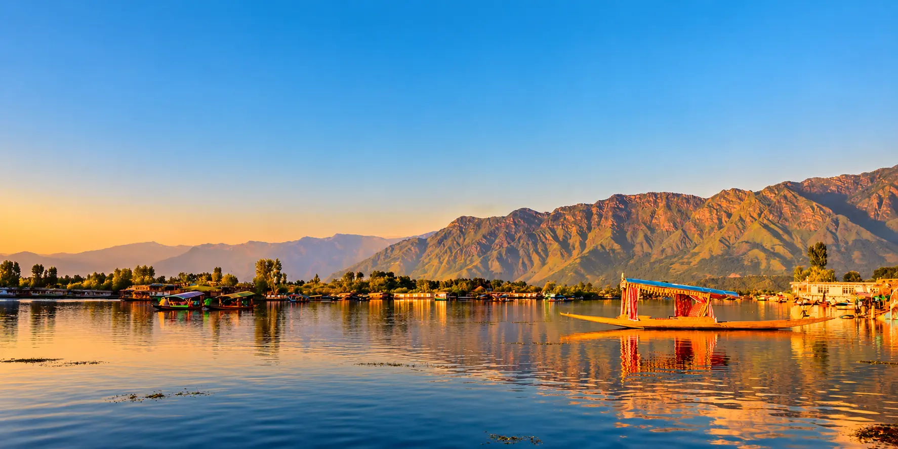 Houseboats on Dal Lake beneath the snow-capped Zabarwan range